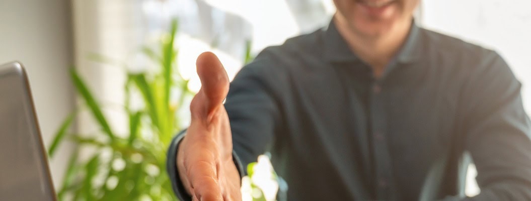 Vertrag per Handschlag in einem Büro mit einem lächelnden Mann